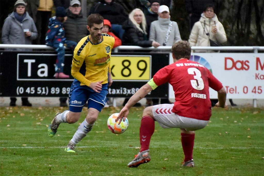 Henrik Sirmais (am Ball, Todesfelde) versucht gegen Nico Fischer (Eichede), der dem SVE Stabilität verleiht, auszuspielen. © 2022 Olaf Wegerich