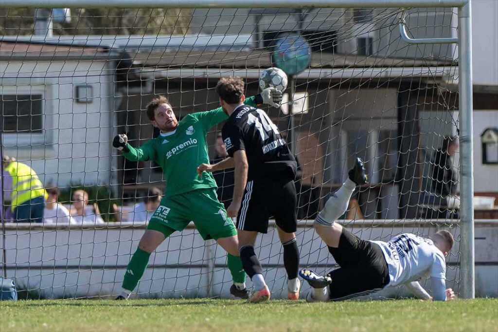 Keeper Eric Gründemann (Heider SV) muss den Ball von fallenden Franz Schlatow (Preußen Reinfeld) zum 1:2 passieren lassen. © 2025 Volker Schlichting
