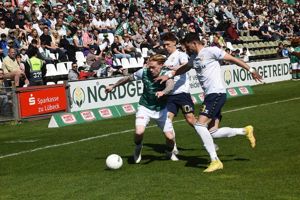 Leon Sommer (VfB Lübeck) wird von Jonathan Stöver und Stelios Kokovas (1. FC Phönix Lübeck) in die Mangel genommen. © 2025 Olaf Wegerich