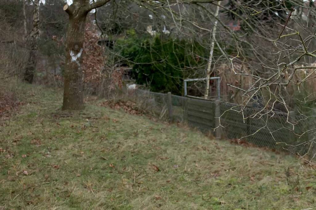 Am Rande des eingeebneten Areals des Paradeplatzes fällt das Gelände teils steil ab. Hier die Grundstücksgrenze zwischen Pestalozzistr. 79 (Modelleisenbahnclub) und Hausnummer 87. Am Rande des eingeebneten Areals des Paradeplatzes fällt das Gelände teils steil ab. Hier die Grundstücksgrenze zwischen Hagebuttenweg 79 (Modelleisenbahnclub) und Hausnummer 87.