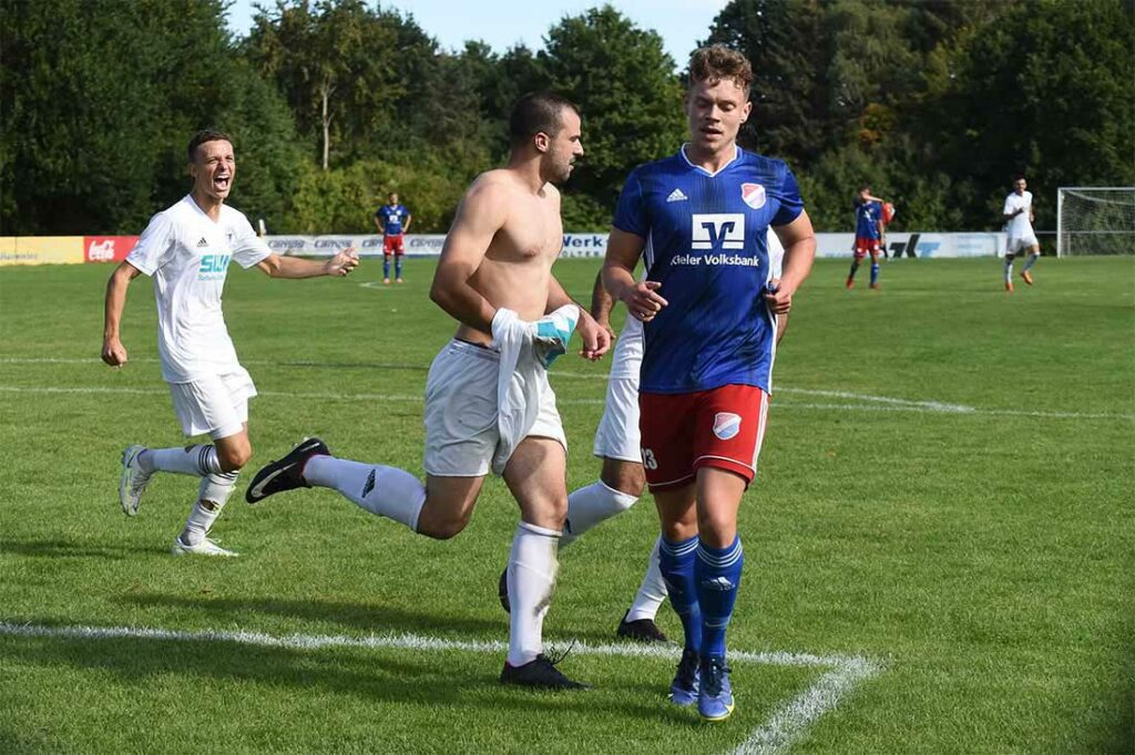 Die endgültige Entscheidung ist Vuk Vukelic (VfR Neumünster) einen Fußball-Striptease wert. Mika Hirsch (li) und Ihab Hathat (von Tom Lenke (Eidertal) verdeckt) sind dabei. Quelle: Olaf Wegerich