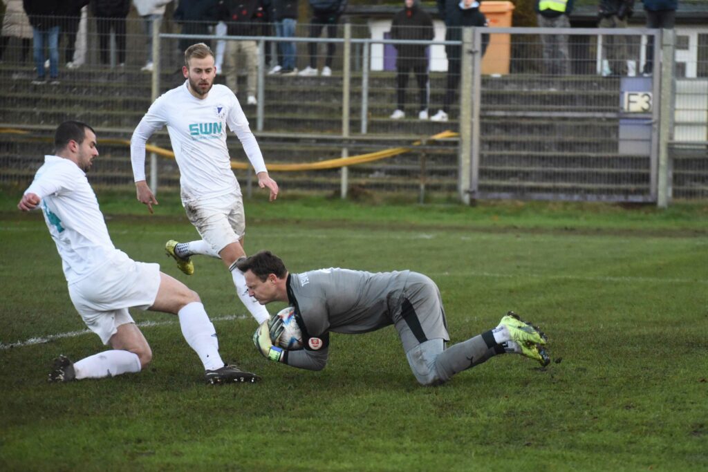 Keeper Tobias Paulat (TSV Klausdorf) klärt vor Vuk Vukelic (VfR Neumünster) beachtet von Jonas Schomaker. © 2022 Olaf Wegerich