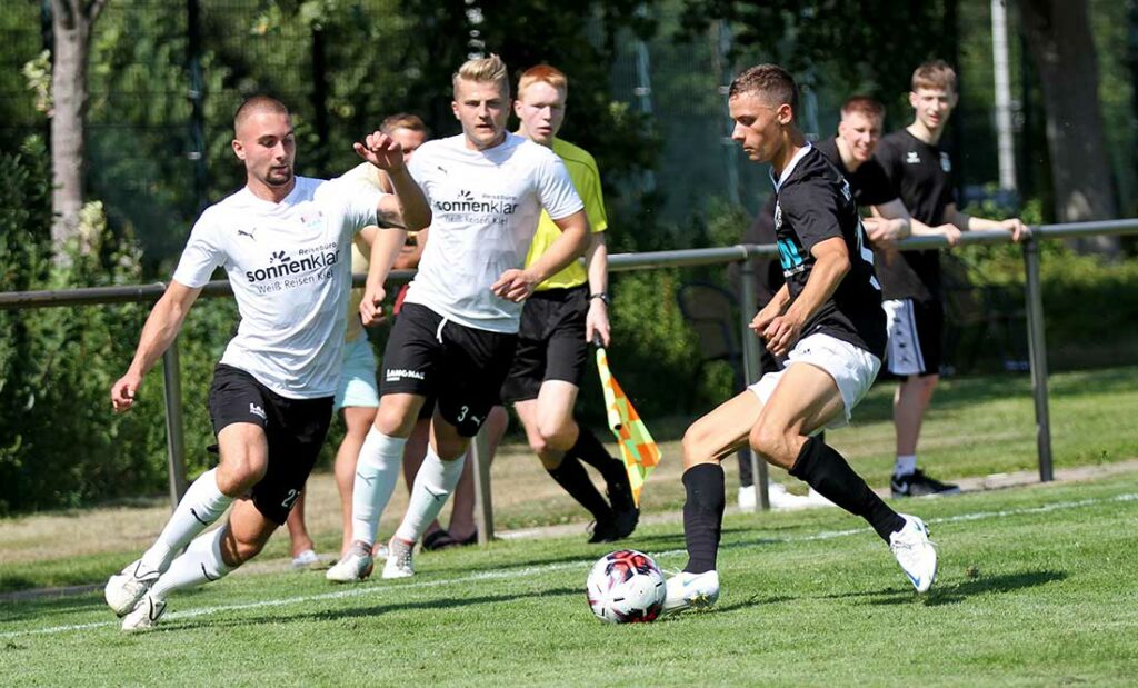 Mika Hirsch (re., Szene aus dem Hinspiel) hatte das Golden Goal für den VfR Neumünster auf dem Fuß. Links Justin Baasch (TSV Kronshagen), im Hintergrund Lasse Baesler. Quelle: Ismail Yesilyurt